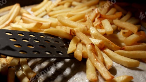 Preview: Closeup of stirring baking french fries in oven with spatula. Fast food, healthy nutrition, cooking