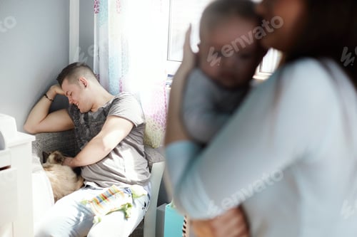 Preview: Mother holding baby and father petting cat at home