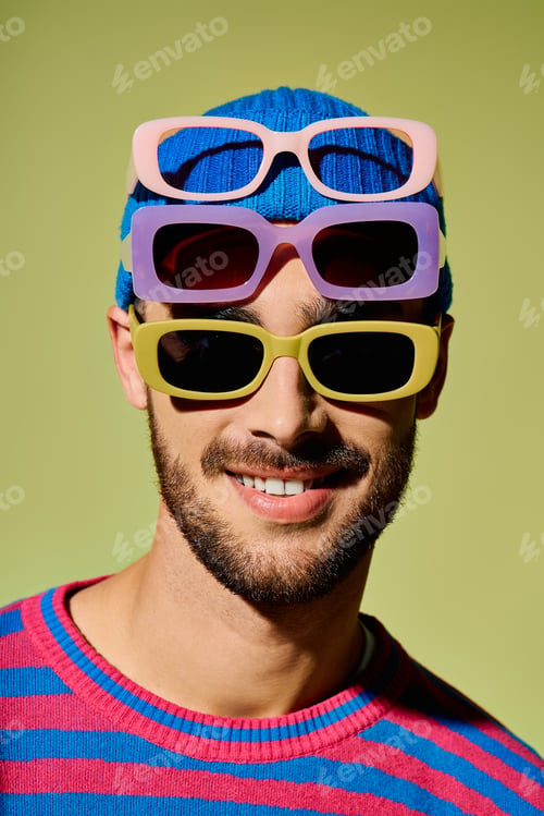 Preview: Stylish young man with trendy sunglasses at a vibrant fashion showcase in a studio