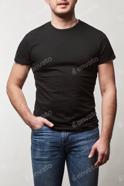 Preview: partial view of man with hand in pocket in denim and black t-shirt with copy space isolated on grey