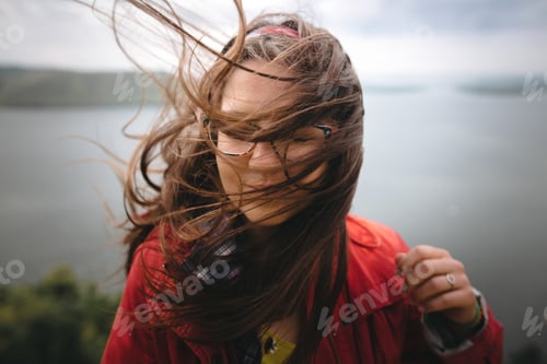 Preview: Young carefree woman in glasses relaxing on cliff