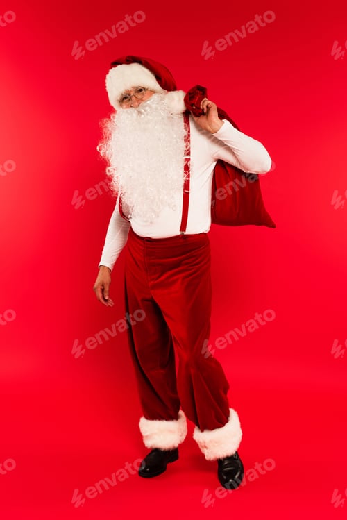 Preview: Santa claus in eyeglasses holding sack on red background