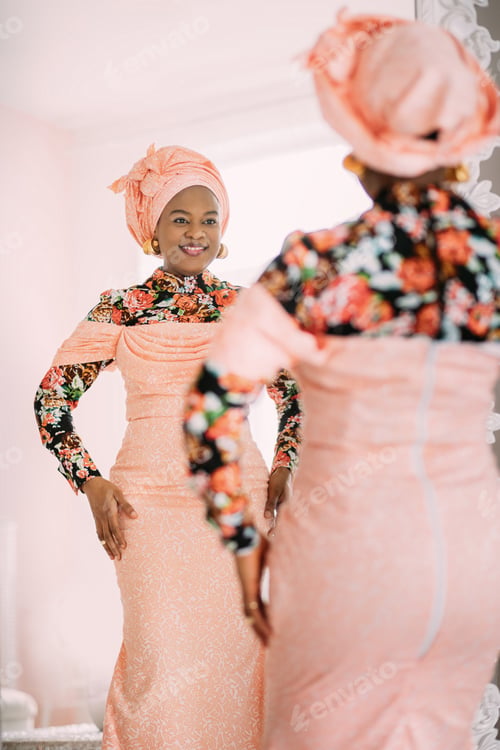 Preview: Studio shot of joyful pretty African lady wearing stylish pink dress with traditional print and