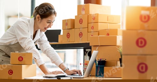 Preview: asian entrepreneur using laptop computer check online order and prepare to packing for customer.