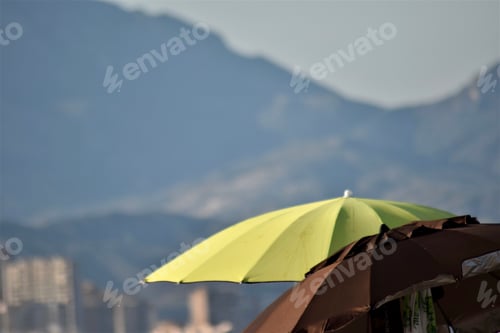 Preview: Beach Umbrellas with City and Mountains Background