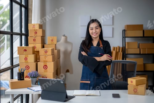 Preview: A woman stands in front of a desk with a laptop and a stack of boxes