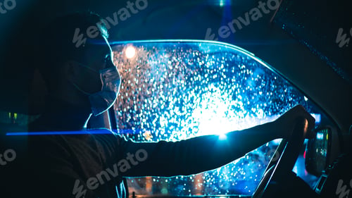 Preview: The man in medical mask drives the car on the night city road.
