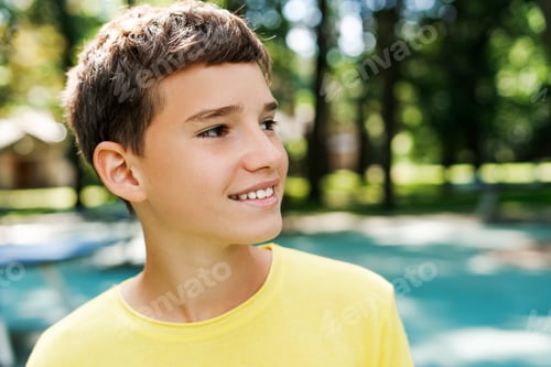 Preview: Smiling teenager boy looking away posing at the park