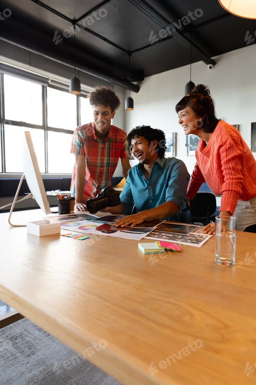 Preview: Happy biracial photographer discussing with multiracial colleagues in meeting at office