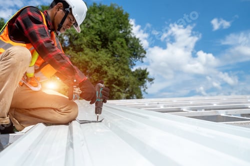 Preview: Roofer working at metal profile roof installation,Roofing tools,Electric drill used on new roofs.