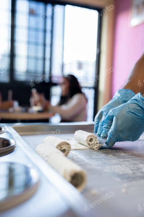 Preview: A worker is using a spatula to roll an ice cream on a freeze machine