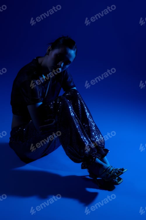 Preview: Stylish young woman displays a trendy outfit in a vibrant studio setting