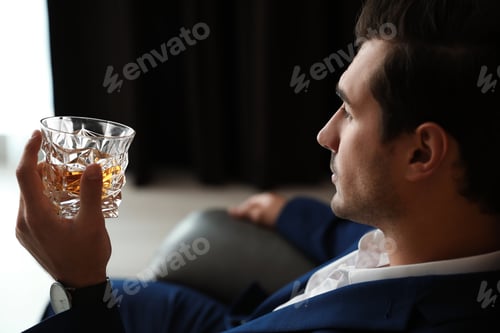 Preview: Young man with glass of whiskey indoors