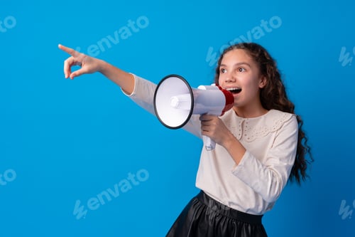Preview: Cute schoolgirl holding megaphone against blue background