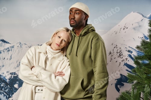 Preview: stylish blonde woman with her head on her boyfriend chest posing on snowy backdrop, winter concept