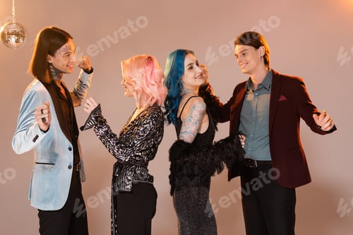 Preview: happy and stylish queer people celebrating christmas and dancing on beige background with pink
