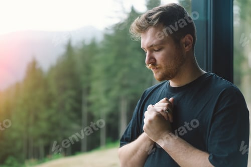 Preview: A man is praying near the beautiful panoramic window against the background of the forest