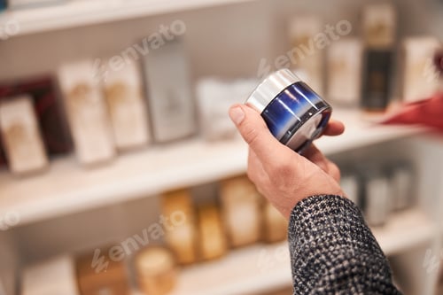 Preview: Hand of a person holding a product of cosmetics in a jar