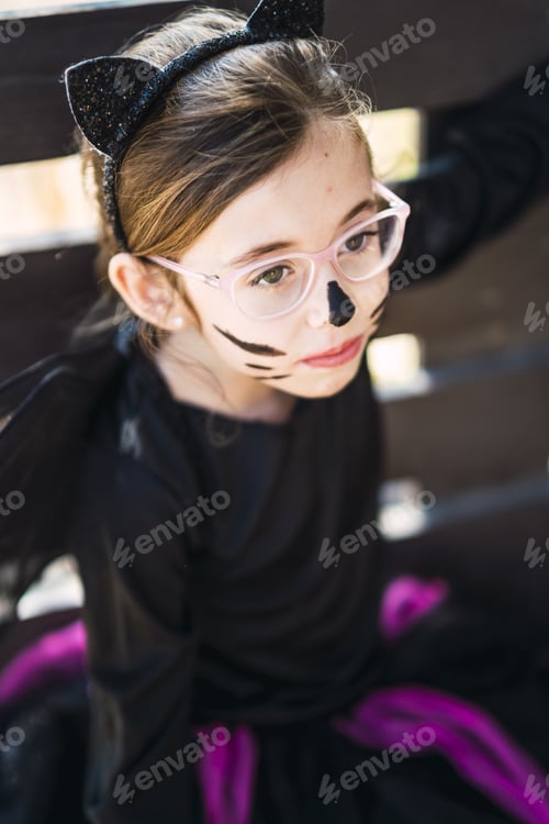 Preview: Portrait of a cute little girl wearing a Halloween cat costume with her face painted