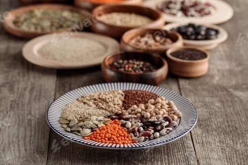 Preview: wooden and ceramic plates with legumes and cereals on brown table