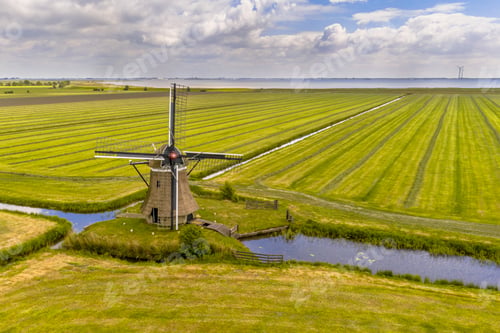 Preview: Old wooden windmill in green agricultural grassland