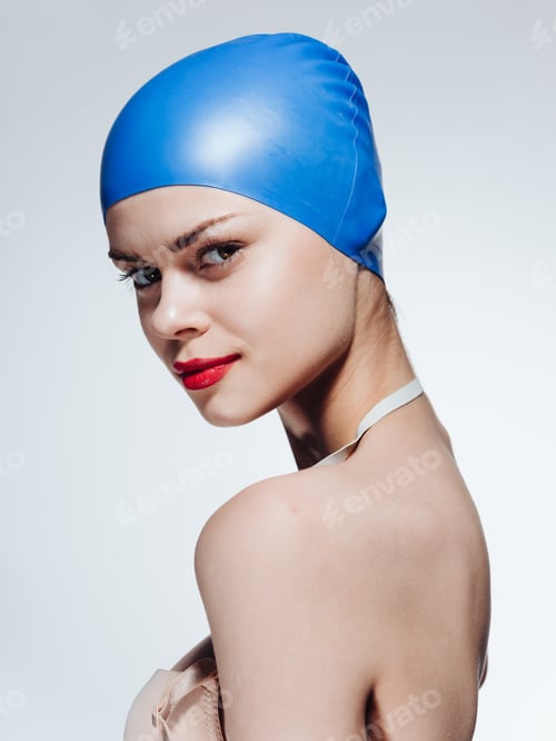 Preview: Side view of a beautiful woman in a blue swimming cap, naked shoulders