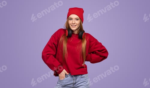 Preview: Delighted teenage lady smiling at camera in violet studio