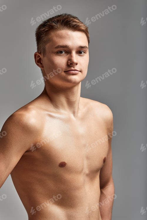 Preview: Young attractive swimmer in excellent physical shape in purple swimming shorts, on a gray background