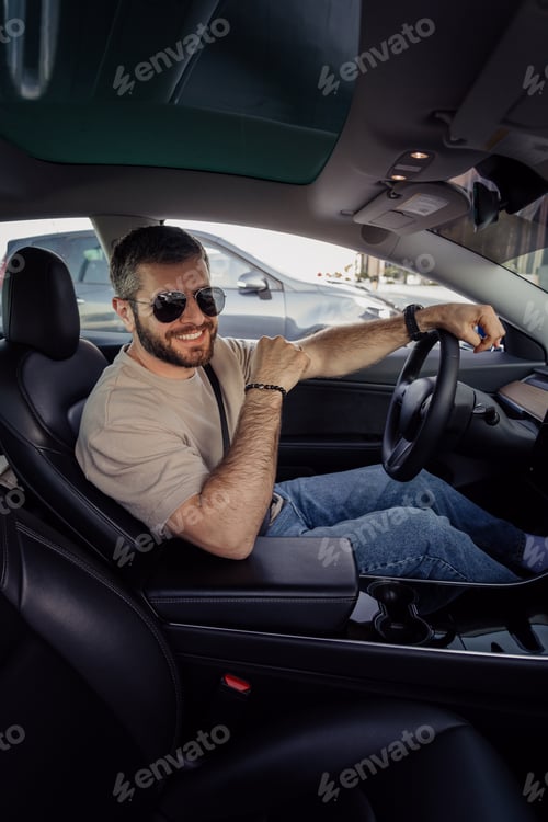 Preview: Smiling man driving an electric car on a sunny day