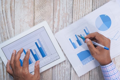Preview: man's hand working on digital tablet at office desk, using self created chart