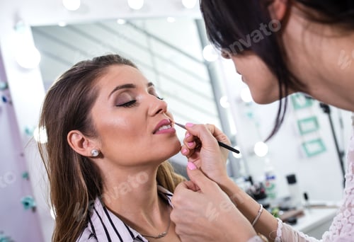 Preview: Female make-up artist applying make up on model in beauty salon.