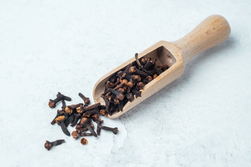 Preview: Scoop of whole cloves on a light textured surface