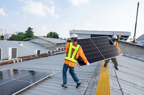 Preview: Team technicians carrying photovoltaic solar moduls on roof.