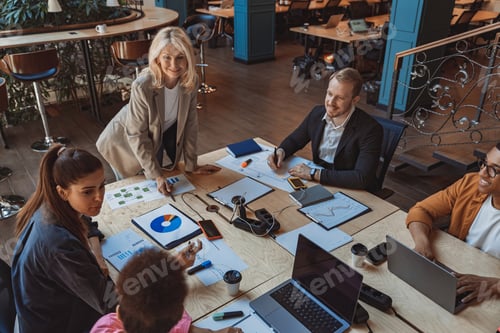 Preview: Group of smiling colleagues is discussing project during meeting in modern coworking