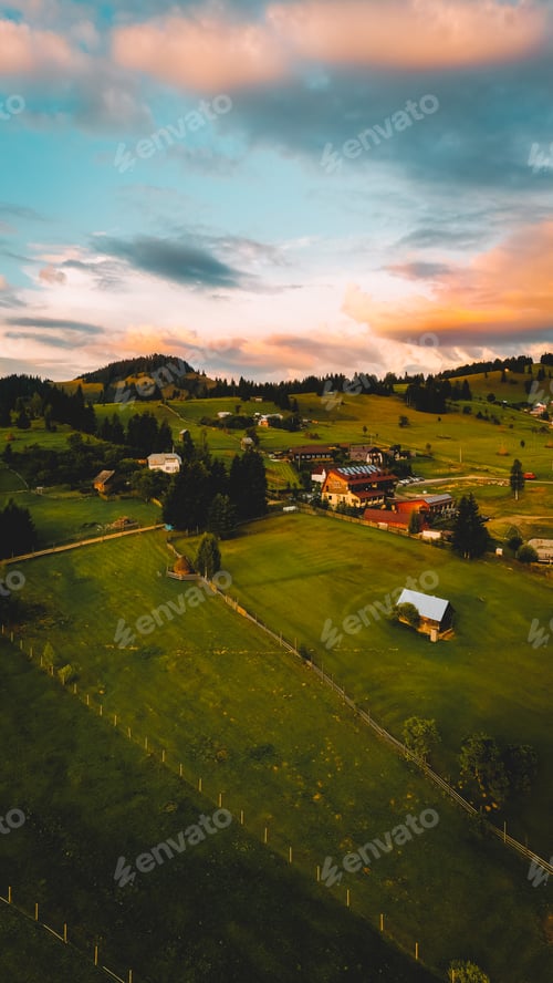 Preview: Charming and beautiful view in nature, colorful sky and clouds, green fields, little houses