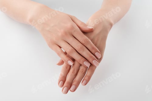 Preview: Partial view of female well-cared clanched hands on white background