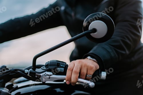 Preview: Male motorcyclist hand twists accelerometer lever while standing at city. Culture and aesthetics