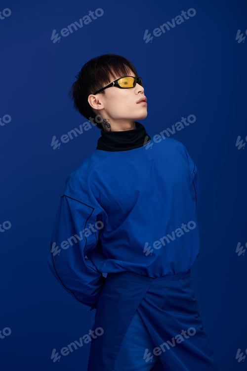 Preview: Stylish young asian man in unique fashion posing against vibrant blue background