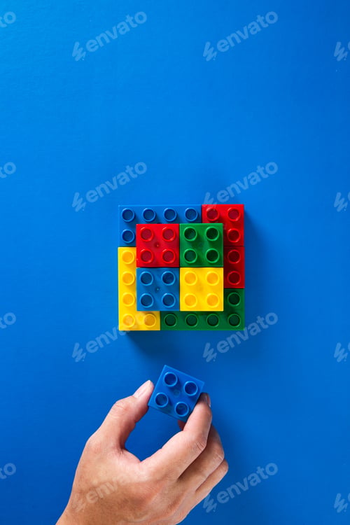 Preview: hand building up a wall by stacking up plastic block