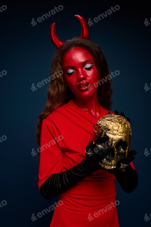 Preview: A captivating woman in a striking Halloween costume holding a golden skull with devilish grace