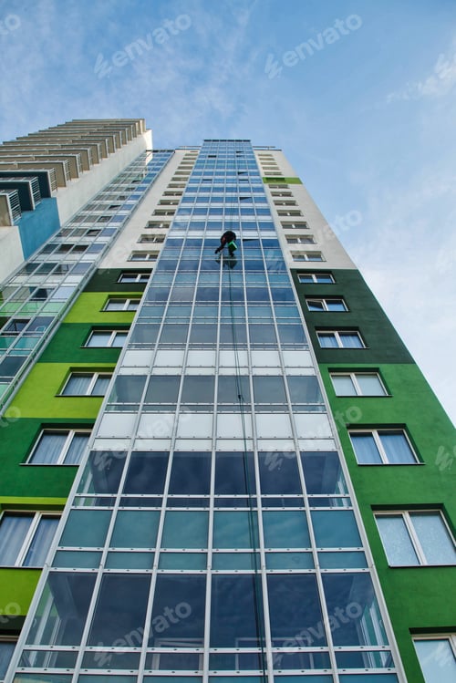 Preview: Industrial Climber Gracefully Cleans the Glazing of a Modern High-Rise Building in Urban Setting