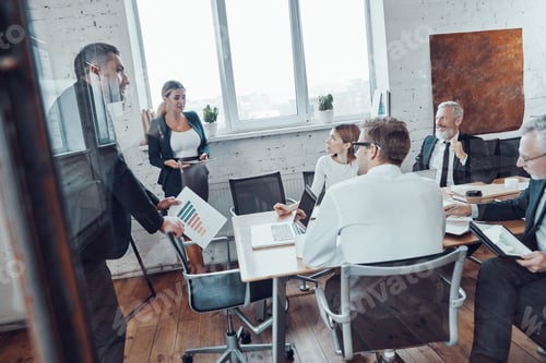 Preview: Successful business team analyzing sales while having staff meeting in the board room