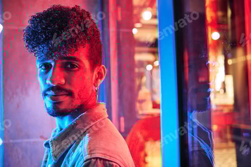 Preview: young hispanic man close to a neon light with blue and red lights