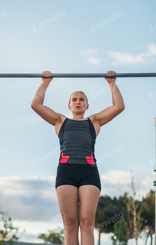 Preview: woman athlete doing pull ups on a bar outdoors. calisthenics