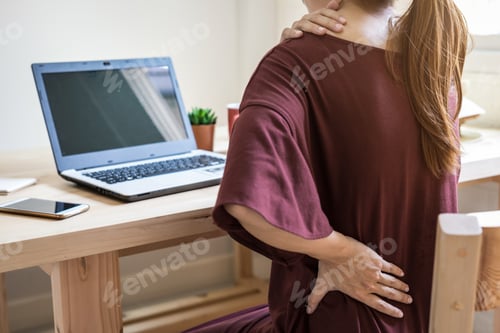Preview: Young woman working at home and having back pain