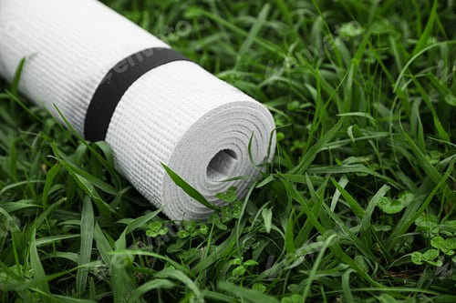 Preview: White karemat or fitness mat on green grass outdoors, closeup