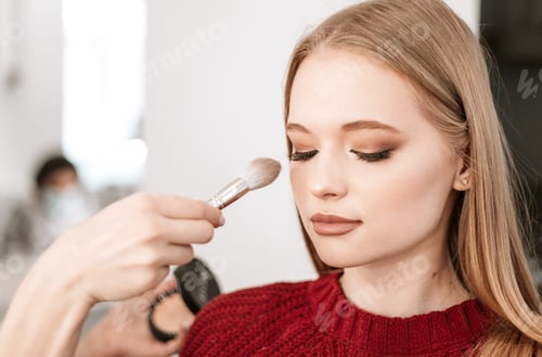 Preview: process of face makeup brush alignment of the face tone on a beautiful young woman model blonde