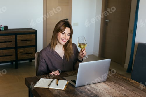Preview: Brunette woman is sitting at laptop chatting online with friends celebrating an important event