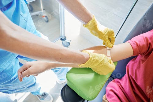 Preview: Blood analysis. Laboratory assistant patches hand of child patient with adhesive plaster after