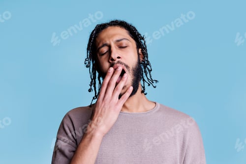 Preview: Tired arab man yawning while covering mouth with hand